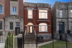 una casa di mattoni con una recinzione di fronte di Comfortable Condo in the Heart of Bronzeville condo a Chicago