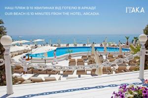 a resort with a pool and chairs and the ocean at Hotel Palladium in Odesa