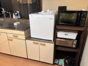 eine Küche mit einem weißen Kühlschrank und einer Mikrowelle in der Unterkunft Kumamoto Castle House in Kumamoto