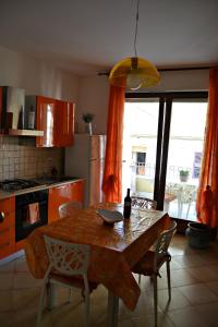 アルゲーロにあるAppartamento Vacanze Algheroのキッチン(テーブル、椅子付)、キッチン(オレンジ色のカーテン付)