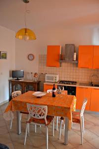 アルゲーロにあるAppartamento Vacanze Algheroのキッチン(オレンジ色のキャビネット、テーブル、椅子付)