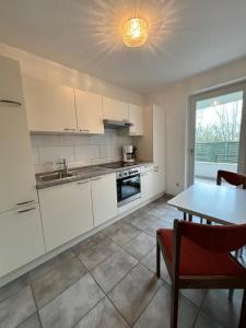 une cuisine avec des placards blancs, une table et une fenêtre dans l'établissement Appartementhaus Westphal Fehmarn, à Fehmarn