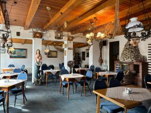 un restaurante con mesas y sillas y una mujer de pie en una habitación en Hotel-Restaurant Cafe Caro en Carolinensiel