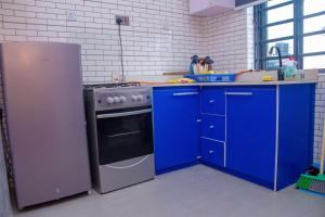 uma cozinha com armários azuis, um fogão e um frigorífico em Bellevue Apartment em Lagos