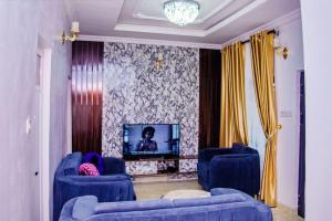 uma sala de estar com duas cadeiras azuis e uma televisão em Bellevue Apartment em Lagos