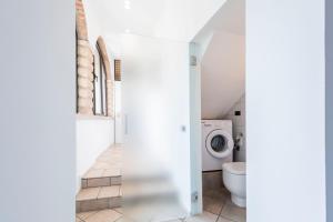 bagno bianco con servizi igienici e lavatrice. di mirko apartment a Verona