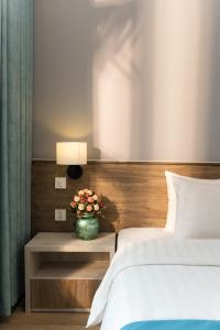 un dormitorio con 2 camas y una mesa con un jarrón de flores en Capital Garden Hotel, en Hanói