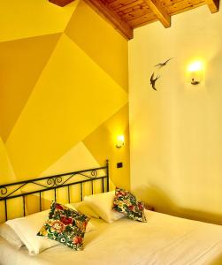 a bed with two pillows and a bird on the wall at Dependance Pesce d'Oro in Verbania
