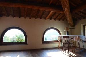 two arched windows in a room with a table and chairs at Collerosso Appartamenti per vacanze in Calci
