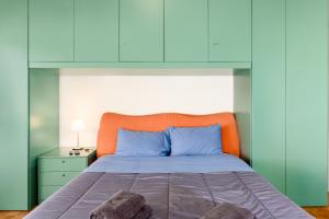 łóżko z niebieskimi poduszkami i pomarańczowym zagłówkiem w obiekcie [Zona Stadio Olimpico] Ampio Bilocale con Balcone w Turynie