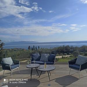 een patio met stoelen en een tafel met uitzicht op de oceaan bij villa Shades of blue in Trapezaki