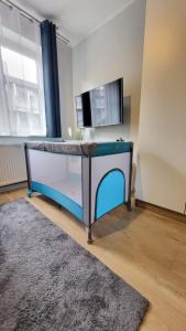 a bed in a room with a tv on a wall at Studio Cicha in Krynica Zdrój