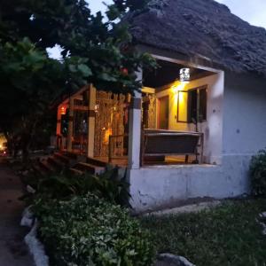 una casa con un banco en el porche por la noche en Fontaine Garden Village en Bwejuu