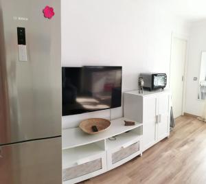 a white entertainment center with a tv and a refrigerator at Estudio reformado primera linea playa in Sitio de Calahonda