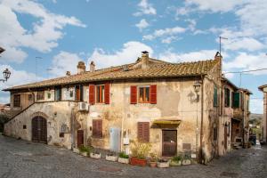 an old stone house with red shutters on a street at Centro e Spiaggia ambra in Anguillara Sabazia