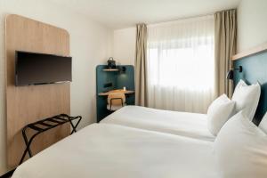 a hotel room with two beds and a tv at Le Carline, Sure Hotel Collection by Best Western in Caen