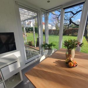 a table with a bowl of fruit on it in a room with windows at Zelfstandig gastenverblijf in het groene Haren nabij Groningen in Haren