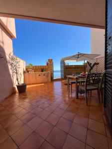 eine Terrasse mit einem Tisch, Stühlen und einem Sonnenschirm in der Unterkunft Gioia di Mare in Marzamemi