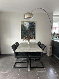 ein Esszimmer mit einem Tisch mit Stühlen und einem Gemälde in der Unterkunft Cube - Ferienhaus mit Garten und Terrasse in Eberbach in Eberbach