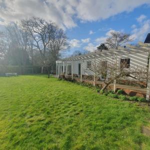 uma casa branca com um campo verde em frente em Zelfstandig gastenverblijf in het groene Haren nabij Groningen em Haren