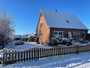 een stenen huis met een hek in de sneeuw bij FeWo Deichblick Wischhafen in Wischhafen