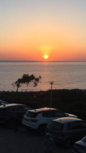 a sunset over the ocean with cars parked in a parking lot at Villetta a Schiera - Bosa Marina in Magomadas