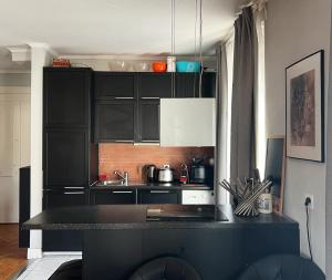 een keuken met zwarte kasten en een zwart aanrecht bij Appartement en centre-ville in Genève