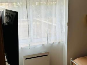 uma janela com uma cortina branca num quarto em La Pomme de Pin em Scionzier