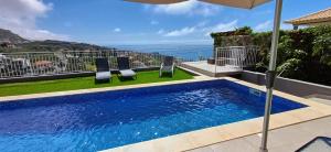 - une piscine avec 2 chaises et un parasol dans l'établissement The Tree of Life House, à Ponta do Sol