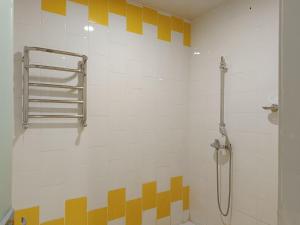 La salle de bains est pourvue d'une douche avec des carrés jaunes sur le mur. dans l'établissement ART SAMARQAND HOTEL, à Samarcande
