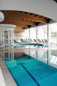 a swimming pool with chairs in a building at Apartma Bazilika in Topolšica