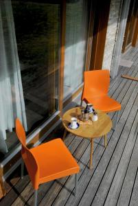 2 sillas naranjas y una mesa de centro en un porche en Apartma Bazilika en Topolšica