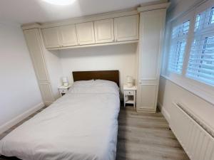 a white bedroom with a bed and two windows at Home near London Heathrow, Slough,Windsor,Legoland in Colnbrook