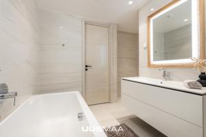 un bagno bianco con vasca e specchio di Das Haus Apartment#Luxury residential#Balcony#Free parking a Tallinn
