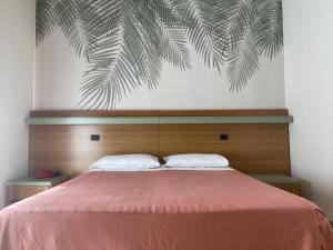 Schlafzimmer mit einem Bett mit rosa Tagesdecke in der Unterkunft Hotel Pine Beach in Rosolina Mare