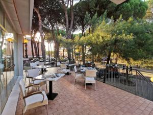 un restaurant avec des tables et des chaises sur une terrasse dans l'établissement Hotel Pine Beach, à Rosolina Mare