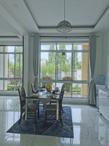 a dining room with a table and chairs and large windows at JNH_HAVEN in Dar es Salaam