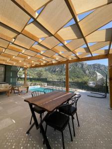 a patio with a wooden table and chairs under a roof at Villa Örencik in Fethiye