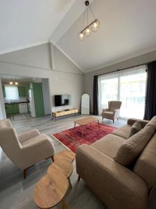 een woonkamer met een bank en stoelen en een tv bij Villa Örencik in Fethiye