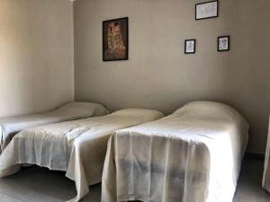 2 bedden in een kamer met witte lakens bij Casa - La Masca - Alla porta delle Langhe in Cherasco