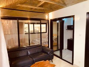 a living room with a leather couch and a bedroom at Résidence Kali in Guediawaye
