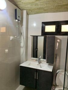 uma casa de banho com um lavatório, um espelho e um WC. em Résidence Kali em Guediawaye