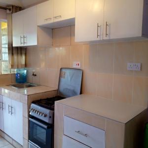 a kitchen with white cabinets and a stove top oven at Verona Airbnb in Thika