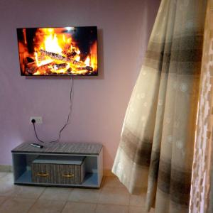a fire in a living room with a tv on a wall at Verona Airbnb in Thika