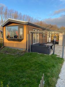 een klein huis met een patio en een tafel bij Chalet op 5 ster CampingPark Capfun de Bongerd in Tuitjenhorn