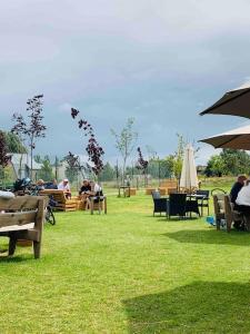a group of people sitting on benches in a park at Blueberry Cottage - Lower Mill Estate in Somerford Keynes