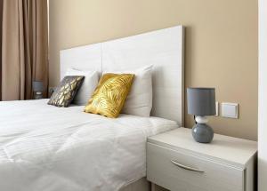 a bedroom with a white bed with two yellow pillows at Miami Apartments in St. Julianʼs