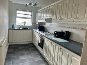 a kitchen with white cabinets and a stove top oven at Auckland House 3 beds free parking in Doncaster