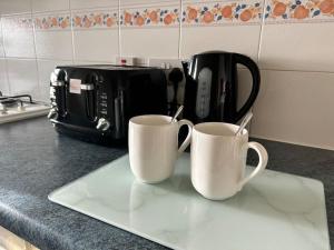 two coffee mugs sitting on top of a kitchen counter at Auckland House 3 beds free parking in Doncaster