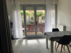 a room with a table and chairs and a sliding glass door at Le Beaulieu appartement T1 Bis RDC classé 3 étoiles avec parking à Barbotan in Cazaubon